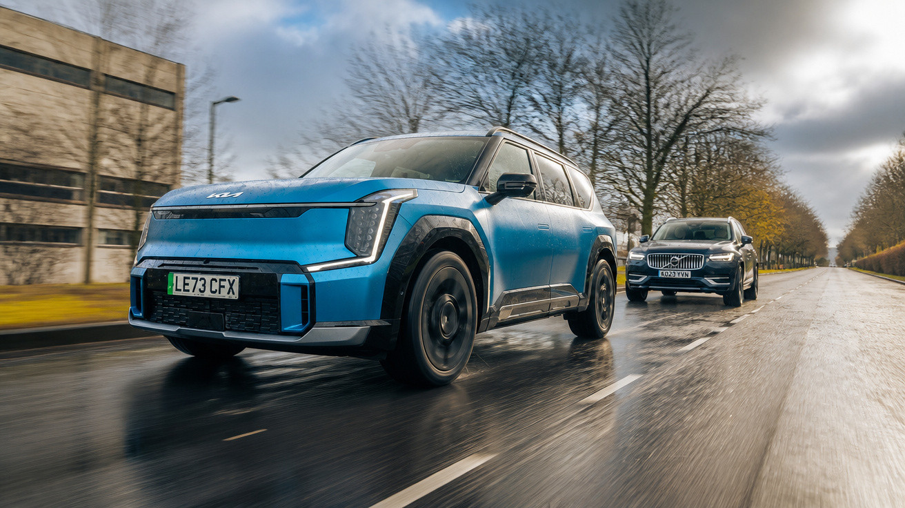 Blaues Kia SUV fährt bei nassem Wetter auf der Straße, schwarzes Auto folgt im Hintergrund, Bäume und Gebäude sichtbar.