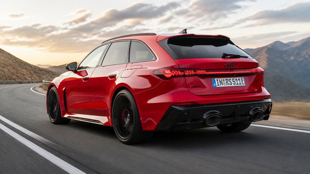 Roter Audi RS Avant fährt auf kurviger Gebirgsstraße bei Sonnenuntergang.