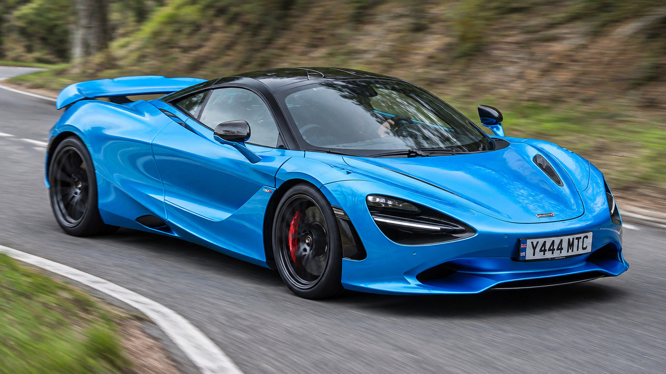 Blauer McLaren-Sportwagen fährt auf kurviger Landstraße mit unscharfem Hintergrund aus Bäumen und Gras.