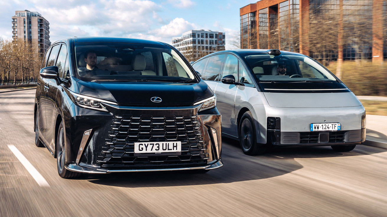 Zwei moderne Autos, ein schwarzer Lexus und ein weißes Fahrzeug, fahren nebeneinander auf einer Stadtstraße.